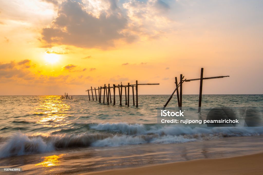 The old and broken wooden bridge The old and broken wooden bridge on the beach with sunset Beauty In Nature Stock Photo