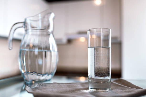 A glass of fresh water with crafin on the background of a modern kitchen. stock photo