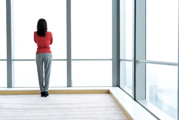 istock Woman standing and looking through the window 1137474241