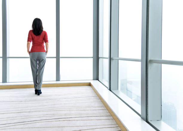 istock Woman standing and looking through the window 1137474402
