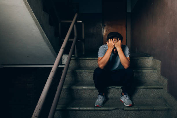 istock Depressed man sitting on the stairs in building and holding his forehead while having headache.Depression concept 1137479557