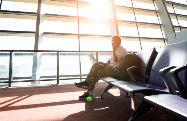 istock Man using smart phone and laptop in airport 1137485216
