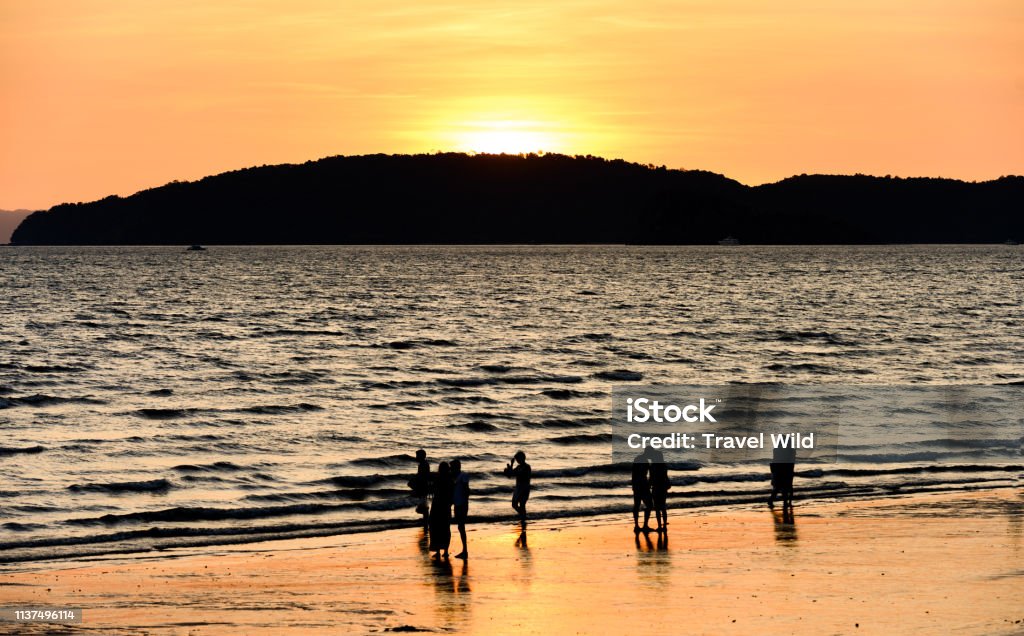 (long exposure) Blurry silhouette of some non unidentified people enjoying the stunning sunset on a beautiful beach bathed by a smooth sea. Ao Nang beach, Krabi Province, Thailand. (Long exposure) Blurry silhouette of some non unidentified people enjoying the stunning sunset on a beautiful beach bathed by a smooth sea. Ao Nang beach, Krabi Province, Thailand. Ao Nang Stock Photo