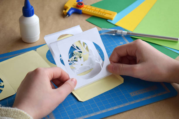 istock Making tunnelbook. 3D greeting card Spring . Artwork equipment and tools for paper cut - cutting knife, sharp box cutter, blue cutting plate, origami paper. Modern 3d origami paper art style. 1137496312