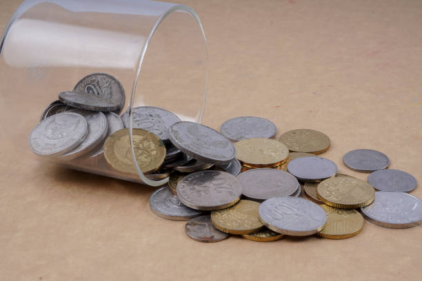 istock Close-Up Of Coins Spilling From Container On Table 1137501731