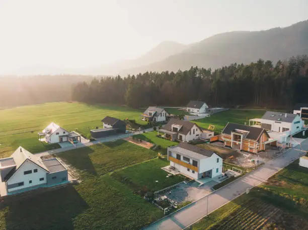 Family homes in the country side in winter time, by the forest. Aerial view, drone point of view, flying over a new housing development. Situated in the country side in Slovenia. Forming a small new neighborhood. Modern architecture had a an influence on design of these new family homes.