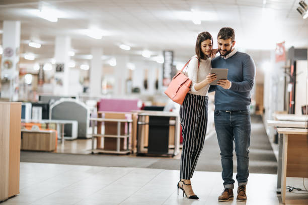 istock Young smiling couple using touchpad while buying in furniture store. 1137506024