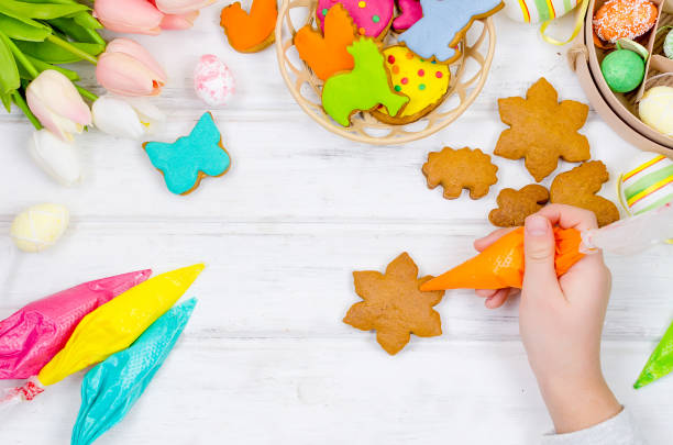 Girl decorating gingerbread with icing for Easter