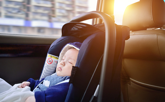 Baby sleeping at car safety seat in moving car.