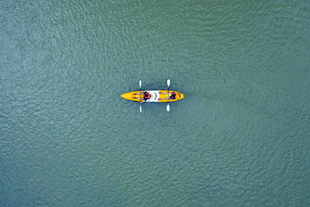 vue d'en haut, superbe vue aérienne de deux touristes qui font du kayak sur la rivière qui traverse le village de vang vieng. vang vieng est situé à environ quatre heures de trajet en bus au nord de vientiane, au laos. - canoe kayak, jaune photos et images de collection