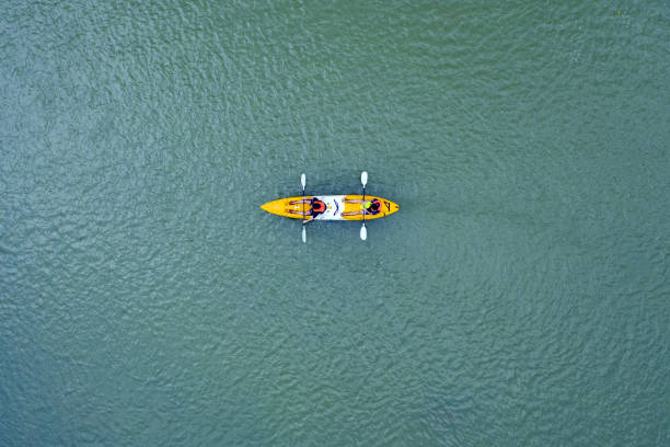 View from above, stunning aerial view of two tourists who are kayaking on the river that runs through the village of Vang Vieng. Vang Vieng is located about four hours bus ride north of Vientiane, Laos. Vang Vieng, Laos, February 17, 2019. Aerial view of two tourists who are kayaking on the river that runs through the village of Vang Vieng. Vang Vieng is located about four hours bus ride north of Vientiane, Laos. rafting kayak kayaking river stock pictures, royalty-free photos & images