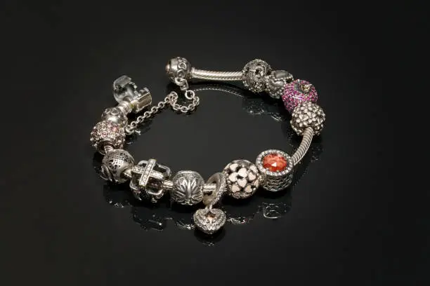 Photo of Women's jewelry bracelet on hand with charms on black background