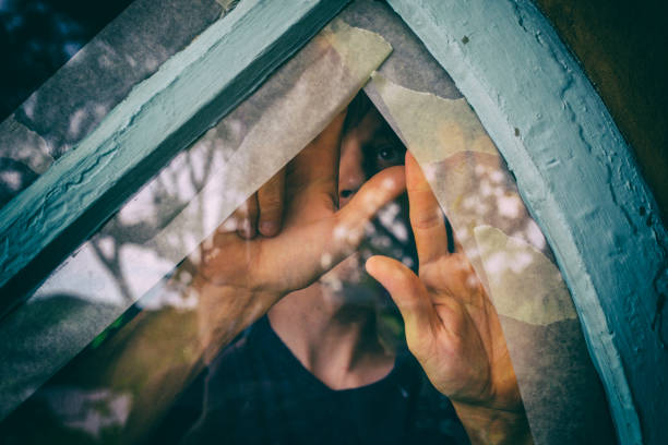 man applies masking tape to a glass window - paint preparation adhesive tape indoors imagens e fotografias de stock