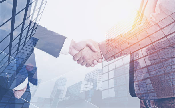 istock Two businessmen shaking hands, skyscrapers 1137525297