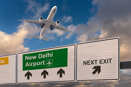 Road sign indicating the direction of New Delhi airport and a plane that just got up.