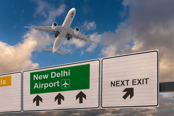 Road sign indicating the direction of New Delhi airport and a plane that just got up. stock photo