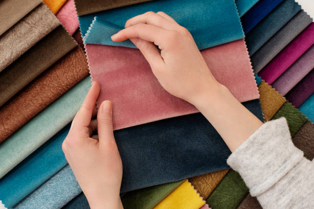 Young woman with fabric samples for curtains at table. Multiple color fabric texture samples selection fabrics for interior decoration. Furniture upholstery Young woman with fabric samples for curtains at table. Multiple color fabric texture samples selection fabrics for interior decoration. Furniture upholstery fabric swatch stock pictures, royalty-free photos & images