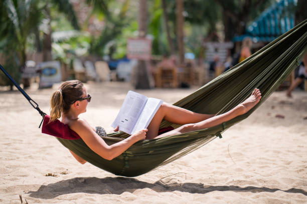 istock Relaxed woman reading a book in hammock on the beach. 1137527800
