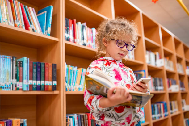istock Little girl in a library using mobile phone 1137538087