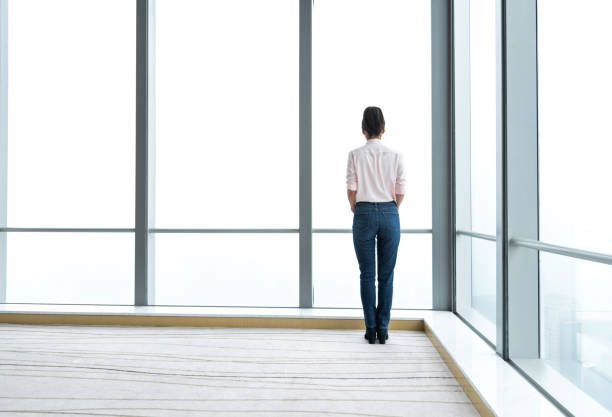 istock Businesswoman standing and looking through the window 1137540783