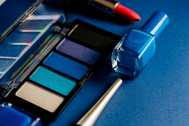 Blue set of eyeshadows, lipsticks and nailpolishes and eyeliners on blue background. Concept product make up.