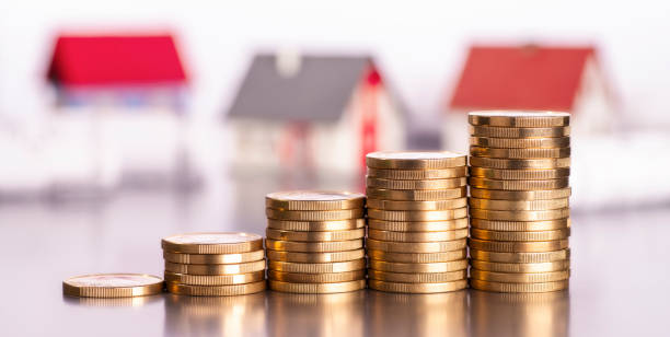 Expensive real estate Rising stacks of coins with houses in the background markup stock pictures, royalty-free photos & images