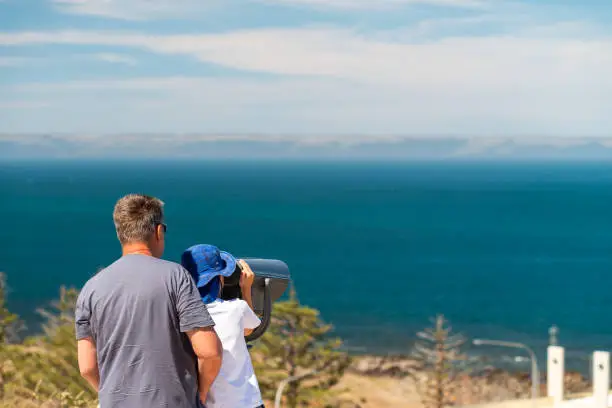 Photo of Grandfather and grandson observing Kangaroo Island coast through outdoor binocular