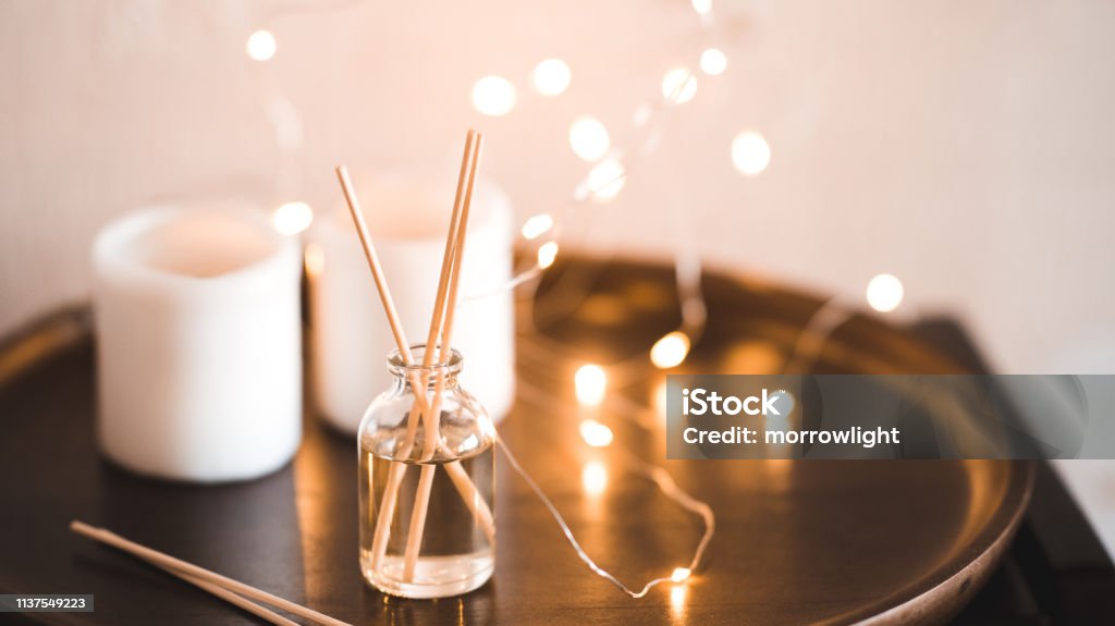 Home fragrance in sticks Aroma sticks with glass bottle over glowing lights at background. Home fragrance. Perfume Stock Photo