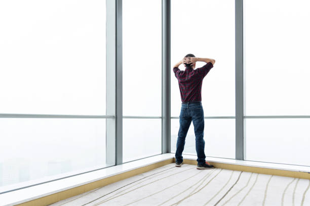 Overworked man standing in front of window.
