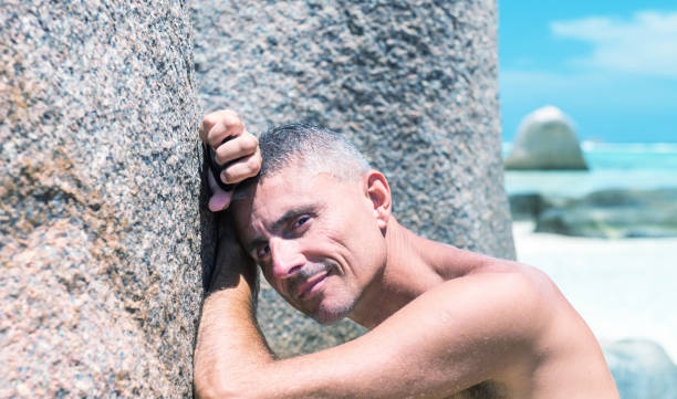 istock Thinking happy man relaxing on the beach leaning on a rock 1137552342