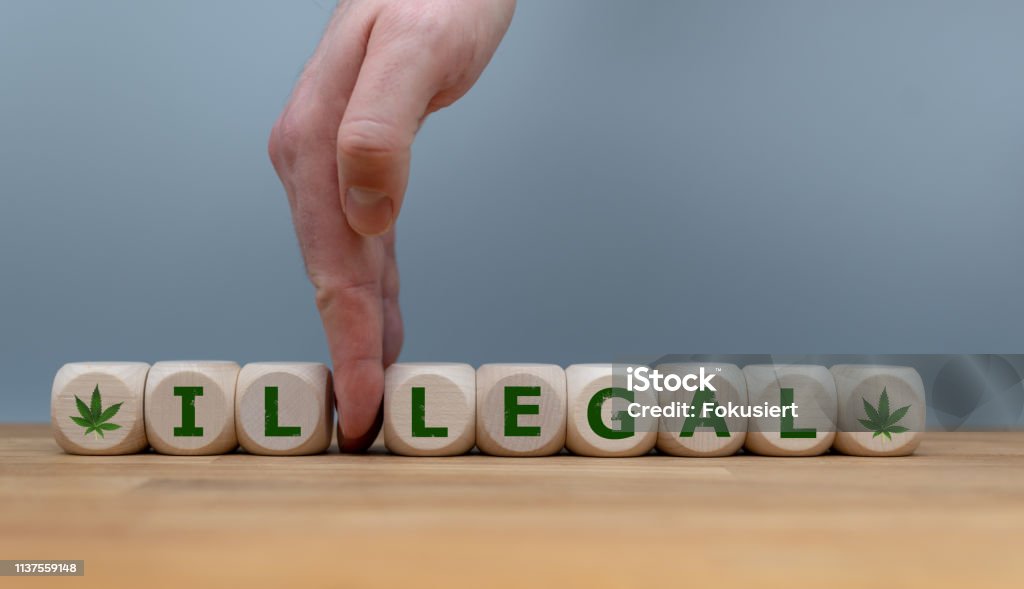 Symbol for Marijuana Legalization. Dice form the word "ILLEGAL" while a hand seperates the letters "IL" in order to change the word to "LEGAL". Cannabis - Narcotic Stock Photo