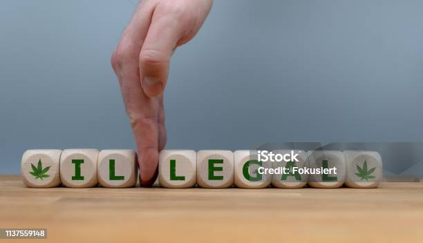 Symbol For Marijuana Legalization Dice Form The Word Illegal While A Hand Seperates The Letters Il In Order To Change The Word To Legal Stock Photo - Download Image Now