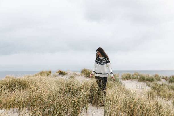 Woman with long hair in wool sweater enjoying a day at the nordic beach on Texel in Netherlands