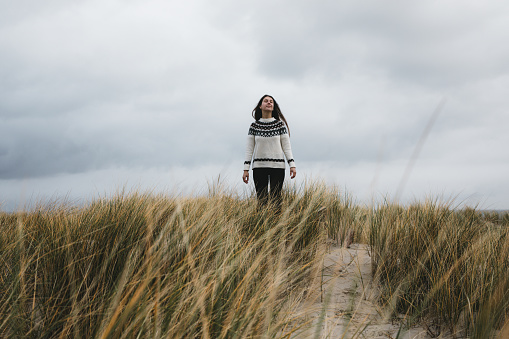 Woman with long hair in wool sweater enjoying a day at the nordic beach on Texel in Netherlands