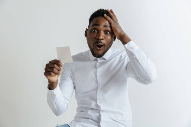 Young afro man with a surprised happy expression won a bet on gray studio background.