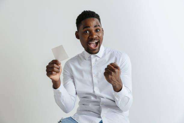 Young afro man with a surprised happy expression won a bet on gray studio background.
