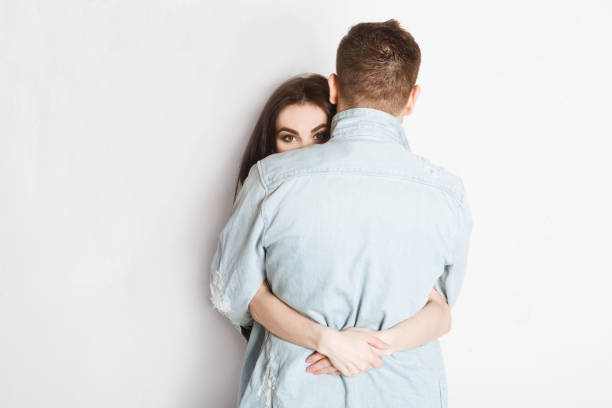 istock woman looking at camera and embracing man on white 1137565963