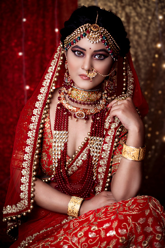 Beautiful young indian girl in bride look wearing red lehanga and gold jewellery