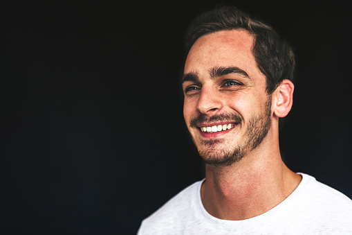 studio shot of smiling happy young handsome man on black background