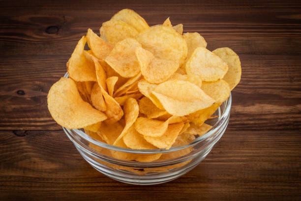 istock Crispy potato chips in bowl on wooden background 1137570028