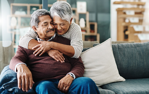 Cropped shot of a cheerful elderly woman hugging her husband who's in a wheelchair at home during the day