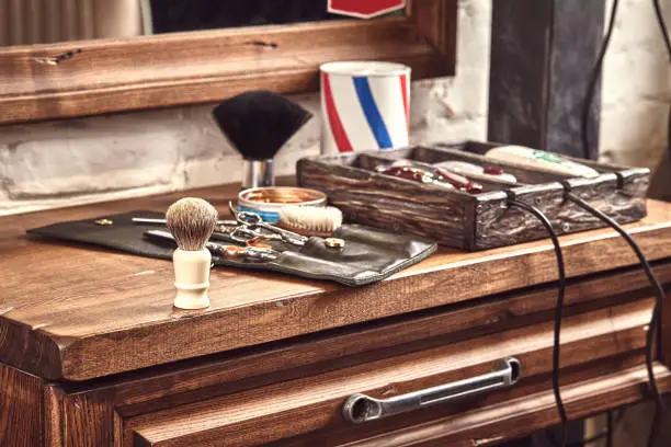 Hairdresser tools on wooden background. Top view on wooden table with scissors, comb, hairbrushes and hairclips, trimmer. Barbershop, manhood concept