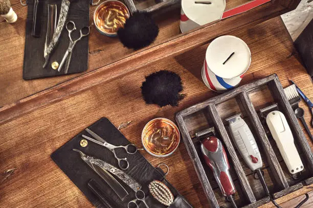 Hairdresser tools on wooden background. Top view on wooden table with scissors, comb, hairbrushes and hairclips, trimmer. Barbershop, manhood concept