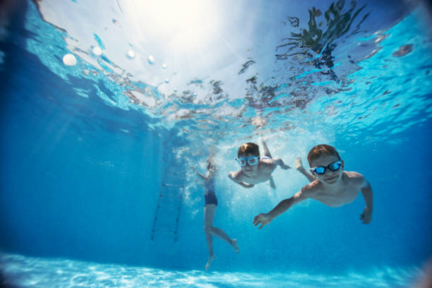 bambini che nuotano sott'acqua in piscina - cheerful swimming pool happiness resort swimming pool foto e immagini stock