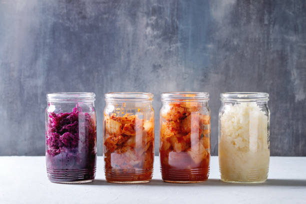 Variety of fermented food Variety of fermented food korean traditional kimchi cabbage and radish salad, white and red sauerkraut in glass jars in row over grey blue table. hot mix plant stock pictures, royalty-free photos & images