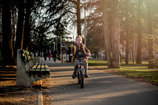 Young blond hair boy cycling through the public park