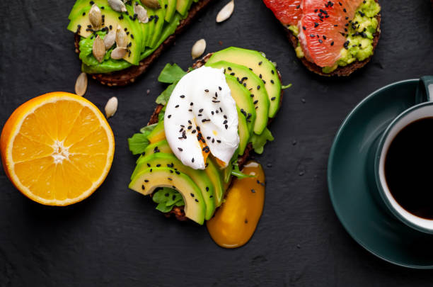 breakfast with avocado, sesame, grapefruit, orange, egg, coffee on a concrete black background