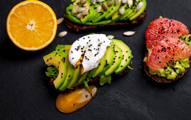 Healthy toasts for breakfast with avocado, sesame, grapefruit, orange, egg on a concrete background
