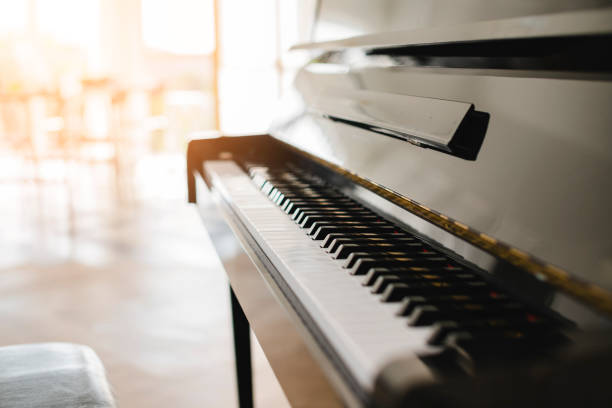 istock black shiny piano with sun light from white curtain window 1137581474