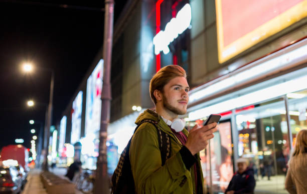 istock Young man using smartphone on urban street at night 1137582640